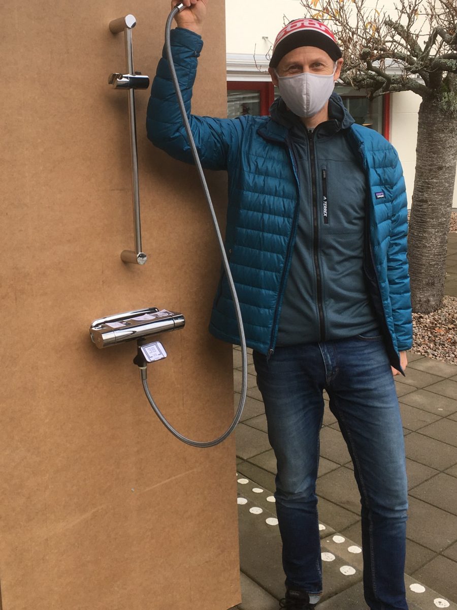 Tobias testar en duschprototyp utomhus med munskydd